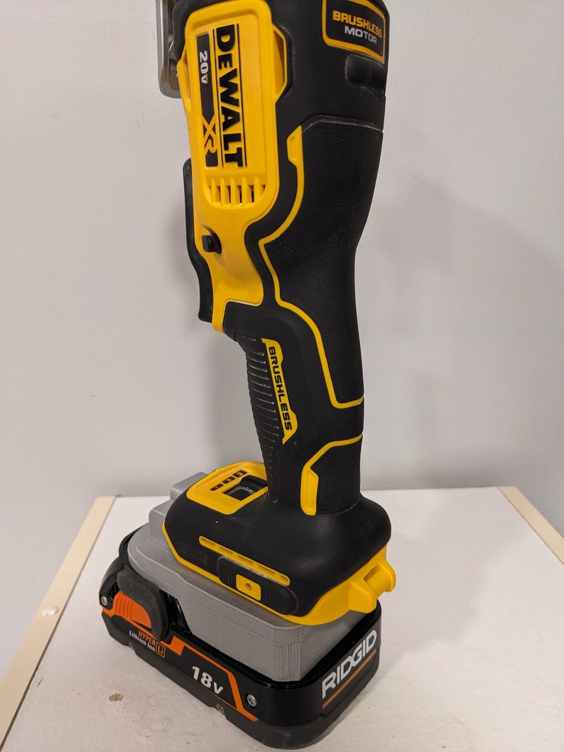 May include: A yellow and black DeWalt 20V XR cordless oscillating tool with a brushless motor is attached to a gray Ridgid 18V battery.
