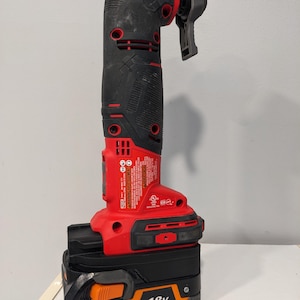 May include: A red and black cordless power tool with a black and orange 18V lithium-ion battery. The tool has a black handle and a red trigger. The battery has the text "HYPER LI Lithium Ion 18V" printed on it.