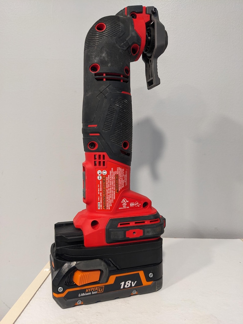 May include: A red and black cordless power tool with a black and orange 18V lithium-ion battery. The tool has a black handle and a red trigger. The battery has the text "HYPER LI Lithium Ion 18V" printed on it.