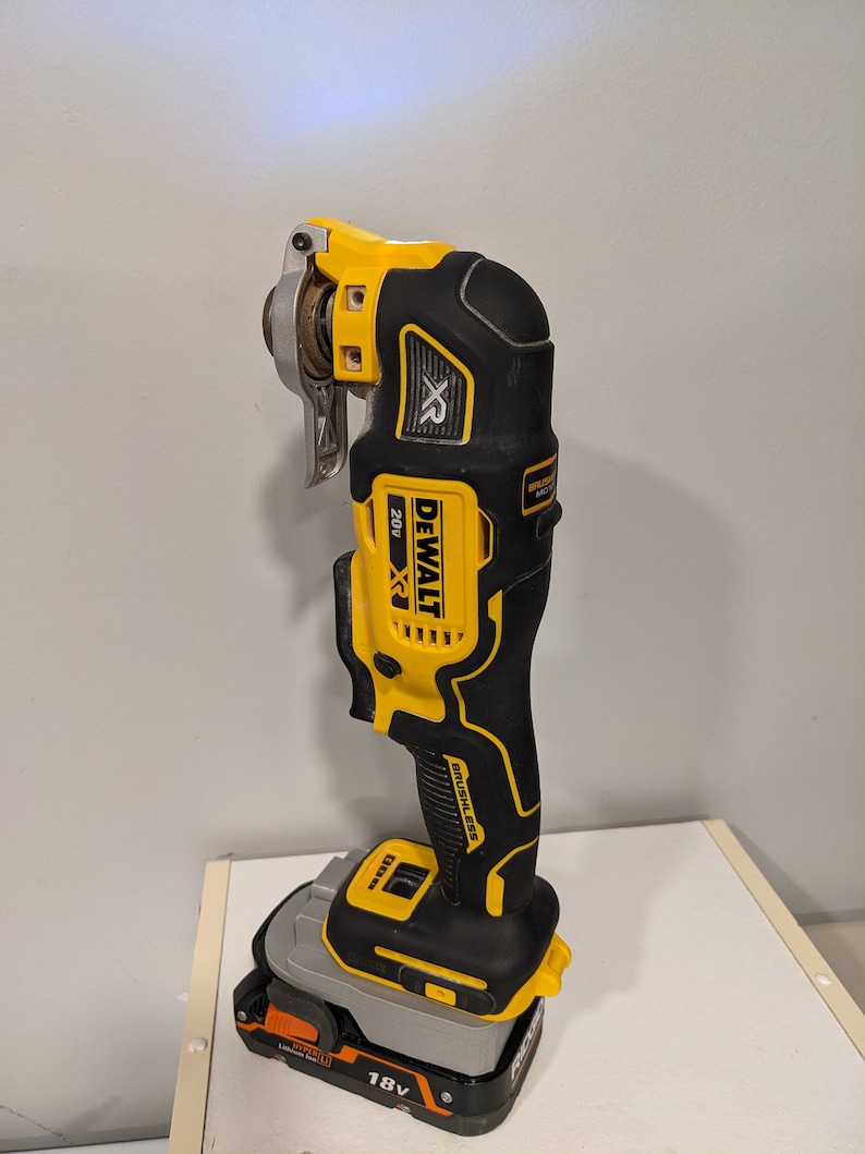 May include: A yellow and black DeWalt 20V MAX XR cordless oscillating tool with a brushless motor and a 18V battery. The tool is on a white surface.