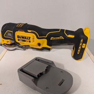 May include: A yellow and black DeWalt 20V XR cordless oscillating tool with a brushless motor. The tool is next to a gray battery charger.