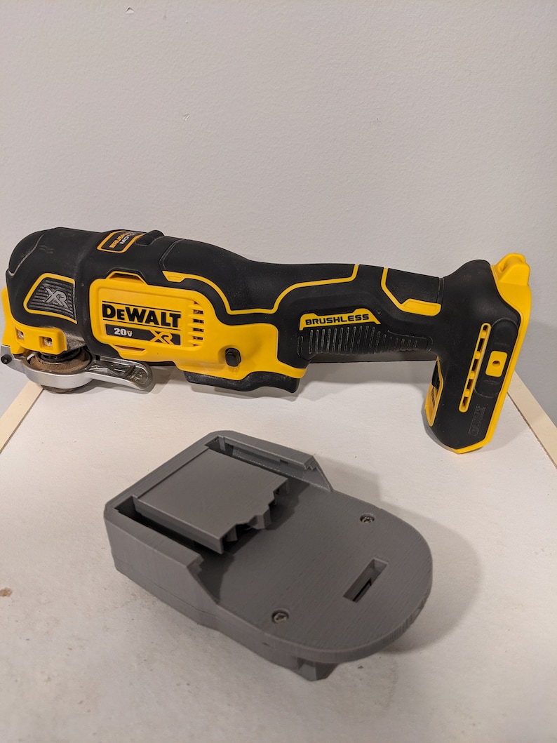 May include: A yellow and black DeWalt 20V XR cordless oscillating tool with a brushless motor. The tool is next to a gray battery charger.
