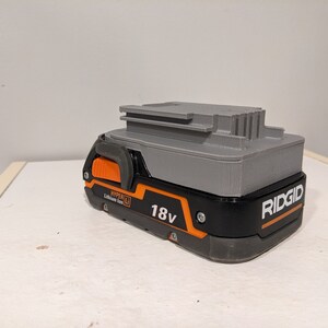 Pu&ograve; includere: Una batteria Ridgid 18V Hyper Lithium-Ion grigia e nera con un pulsante di rilascio arancione.