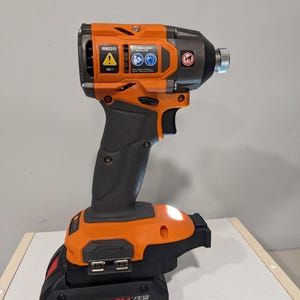 Op de afbeelding: Een oranje en zwarte draadloze schroevendraaier met een CORE18V 4.0 batterij. De schroevendraaier heeft een ingebouwde LED-lamp en een riemclip.