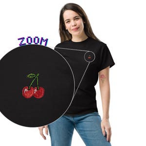 May include: Black t-shirt with an embroidered cherry design on the chest. The cherry design is red with green leaves and stems. The image includes a zoomed-in view of the cherry embroidery.