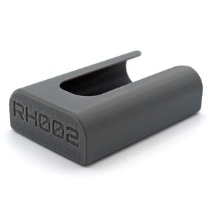 Może przedstawiać: Szara plastikowa obudowa z gniazdem na urządzenie. Na spodzie obudowy znajduje się napis "RHOD2".