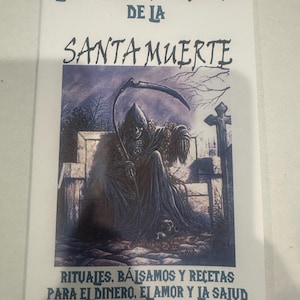May include: A printed image featuring the text "LOS PODEROSOS SECRETOS DE LA SANTA MUERTE" in blue. The image depicts a cloaked figure with a scythe, seated in front of a tombstone. Additional text at the bottom reads "RITUALES, BÁLSAMOS Y RECETAS PARA EL DINERO, EL AMOR Y LA SALUD."