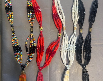 May include: Four beaded necklaces with different colored beads and religious figures as pendants. The necklaces are red, white, black, and multi-colored.