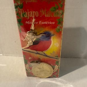 Puede incluir: Caja rectangular con las palabras "Perfume Original" y "Pájaro Macua" en letras doradas. La caja presenta una colorida ilustración de un pájaro posado en una rama, con una moneda de oro en la parte inferior. También se ven las palabras "Místico Esotérico".