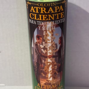 May include: A green glass candle with a black and gold label. The label features the text "ATRAPA CLIENTE" and "ATTRACT CUSTOMERS FOR CUSTOMERS AND LUCK". The image on the label shows two people shaking hands with money falling around them.