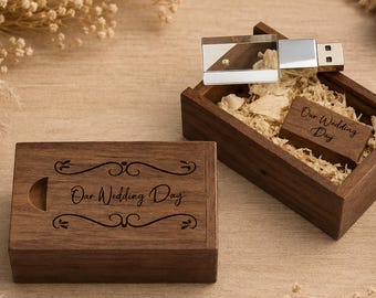 Könnte beinhalten: Eine dunkelbraune Holzschiebebox und ein passender USB-Stick mit silbernem Metallanschluss. Beide Gegenstände sind mit dem Text Our Wedding Day in Schreibschrift graviert. Die Box ist mit hellen Holzspänen als Polsterung gefüllt.