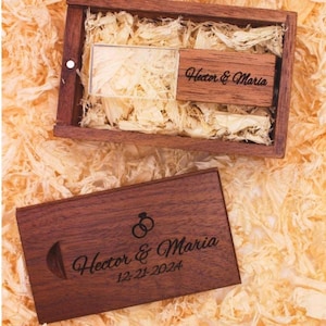 May include: A wooden box with a clear USB drive inside. The USB drive is engraved with the text "Hector & Maria". The box is also engraved with the text "Hector & Maria 12-21-2024" and a pair of interlocking rings.