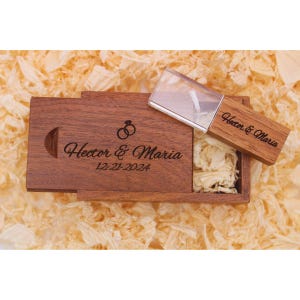 May include: A wooden box with a clear acrylic USB drive inside. The box is engraved with the text "Hector & Maria 12-21-2024" and a ring symbol. The USB drive is also engraved with the text "Hector & Maria".