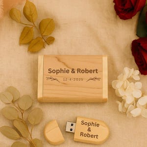 Può includere: Una chiavetta USB e un cofanetto in legno abbinato, entrambi incisi con i nomi "Sophie & Robert" e la data "12-4-2025". Il cofanetto è rettangolare e la chiavetta USB è in due pezzi. Lo sfondo è un tessuto beige chiaro con accenti floreali.