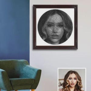 May include: A framed string art portrait of a woman's face. The artwork is created with black thread on a white background, enclosed in a dark brown wooden frame. The portrait is a detailed representation of a woman's features.
