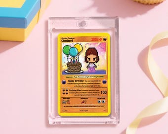 May include: A yellow Birthday Charizard Pokemon card in a clear protective case. The card features pixelated art of a cake, balloons, and a character. Text includes "Happy Birthday!" and "Birthday Blast". The card is on a pink surface.