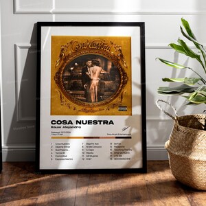 May include: A framed poster with a gold background and a black and white photo of a couple. The poster is titled "Cosa Nuestra" and features the artist Rauw Alejandro. The album's tracklist is printed below the photo.