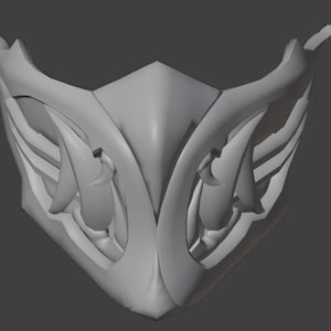 Puede incluir: Una máscara gris estilizada con un diseño simétrico. La máscara presenta elementos curvos en forma de alas y detalles puntiagudos, creando una estética futurista o fantástica. La forma general está diseñada para cubrir la parte inferior de la cara.