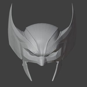 K&ouml;nnte beinhalten: Ein graues 3D-gedrucktes Modell eines Superhelden-Helms mit einer spitzen Oberseite und zwei gro&szlig;en Ohrteilen.