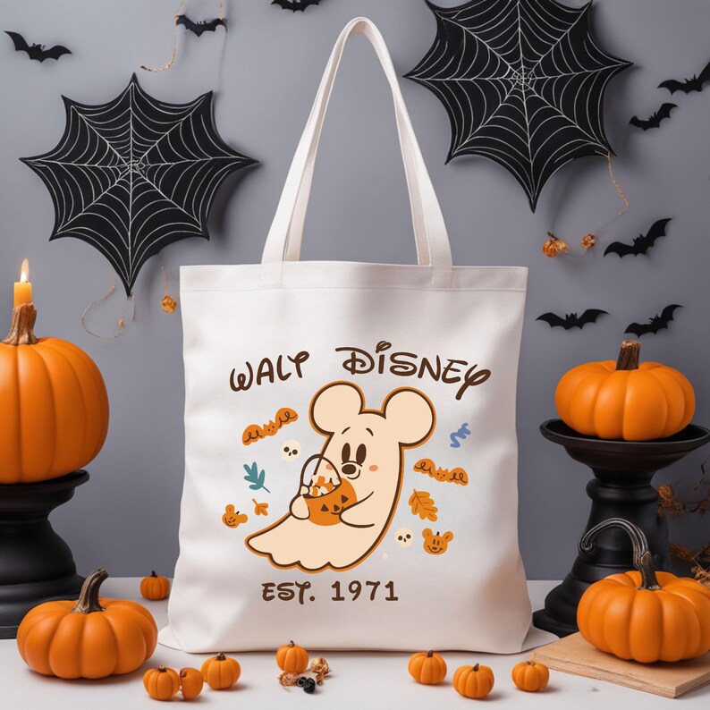 May include: Cream-coloured tote bag with a cartoon ghost holding a pumpkin, and the text "Waly Disney EST. 1971". The image includes Halloween decorations such as pumpkins and bats.