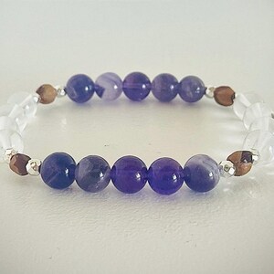 May include: A purple and clear crystal beaded bracelet with silver and brown accents.