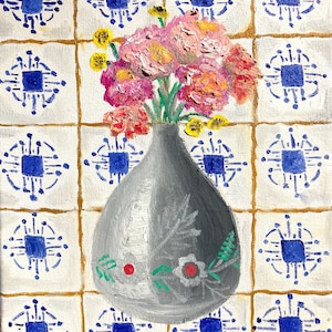 May include: A gray ceramic vase with a floral design sits on a white tiled background. The vase is filled with pink and yellow flowers.