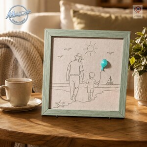 Peut inclure: Une décoration murale carrée encadrée présentant un dessin au trait noir sur un fond en tissu beige clair. L'illustration représente un adulte et un enfant marchant sur une plage, avec un petit ballon turquoise en relief sur la main.