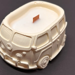 May include: White ceramic candle shaped like a vintage Volkswagen van with a wooden wick.