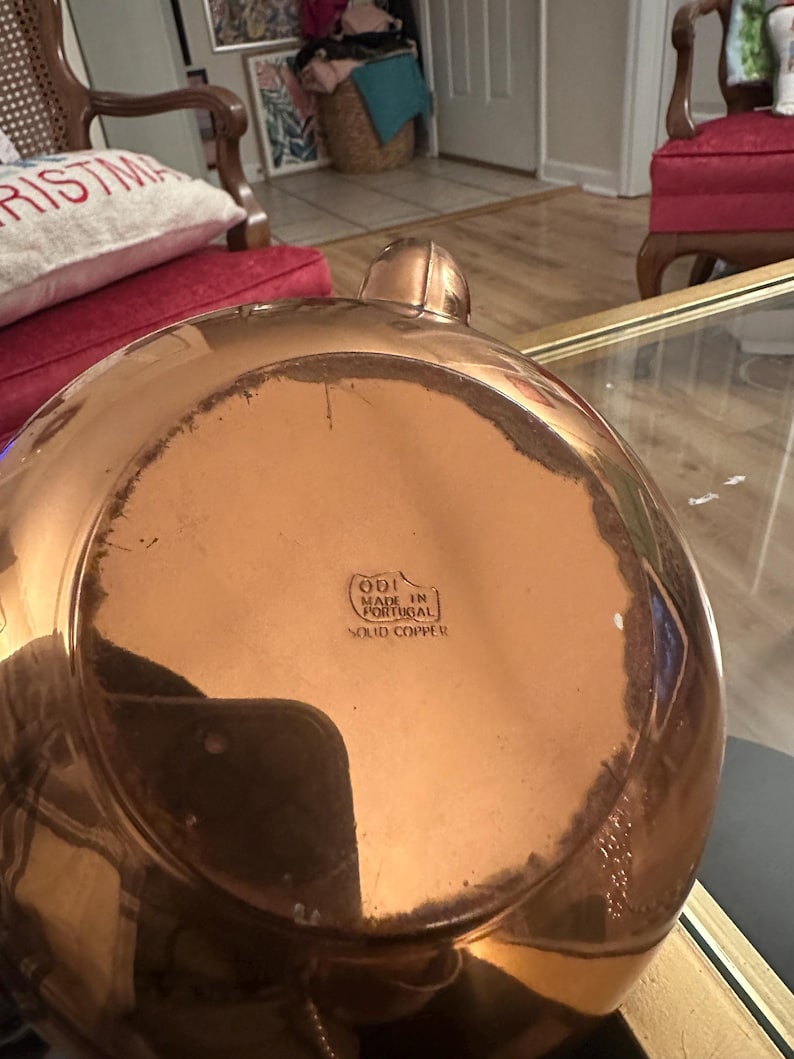 Peut inclure: Une bouilloire en cuivre avec une finition brillante. Le fond de la bouilloire porte une &eacute;tiquette indiquant "ODI Fabriqu&eacute; au Portugal Cuivre massif."