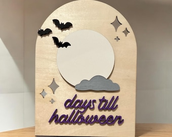 May include: Wooden Halloween countdown sign with a light wood finish. Features a white moon, gray cloud, black bats, and purple text that reads "days till halloween". Decorative star accents complete the design.