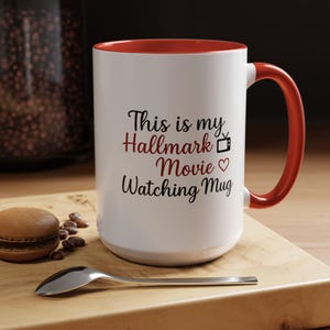 May include: White ceramic mug with a red interior and handle. The mug features the text "This is my Hallmark Movie Watching Mug" in black and red script, with a TV icon and heart symbol.