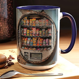 May include: A white ceramic mug with a blue interior and handle. The mug features a detailed image of a vintage vending machine filled with snacks. The design includes a weathered, distressed look, with a dark background.