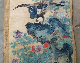 May include: Antique Asian scroll painting featuring a peacock with outstretched wings perched on a blue rock formation. The artwork includes colorful flowers and foliage in shades of red, purple, and green, set against a beige background.