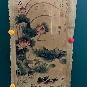 May include: A vintage scroll painting featuring a detailed depiction of lotus flowers and leaves in a pond, with two ducks swimming. The artwork includes Chinese calligraphy and seals, and is held in place by colorful magnets.