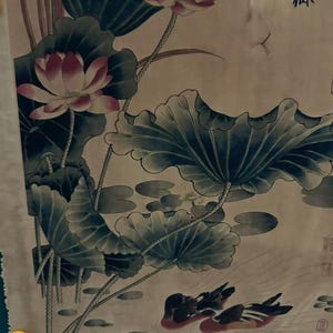 May include: An Asian-style painting featuring lotus flowers with pink and white petals, large green leaves, and two ducks swimming in a pond. The artwork has a muted color palette with a beige background and traditional calligraphy.