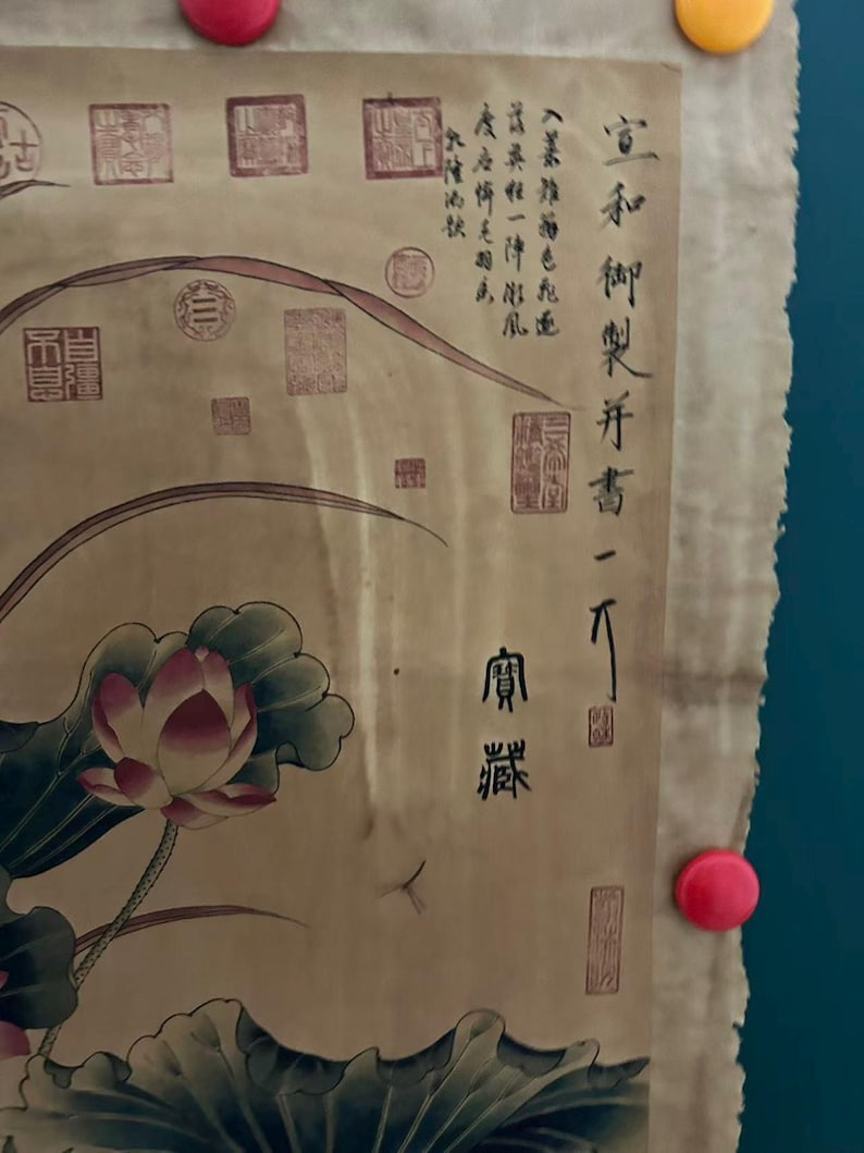 May include: A vintage scroll featuring a watercolor painting of a lotus flower with pink petals and green leaves. The artwork includes Chinese calligraphy and red seals, mounted on a beige background.