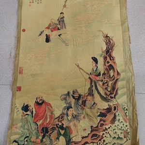 May include: Antique Chinese scroll painting featuring figures in traditional attire. The artwork displays a muted color palette with detailed brushstrokes. The scroll includes Chinese characters and red seals, showcasing a historical narrative.
