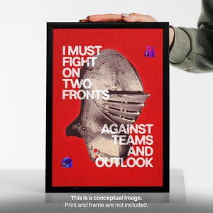 May include: A framed poster featuring a textured, metallic-coloured knight's helmet centred on a vibrant red background. The white text reads: I MUST FIGHT ON TWO FRONTS AGAINST TEAMS AND OUTLOOK. Small purple and blue icons are visible.