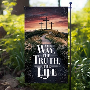 Könnte beinhalten: Eine Gartenflagge mit schwarzem Hintergrund und weißem Text, der "The Way, The Truth, The Life" lautet. Das Hintergrundbild ist ein Sonnenuntergang mit drei Kreuzen auf einem Hügel.