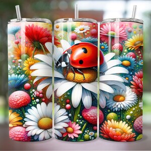 May include: A stainless steel tumbler with a colorful floral design featuring daisies, red flowers, and a ladybug. The tumbler has a straw and a lid.