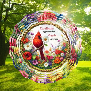 May include: A colorful metal wind spinner with a cardinal and flowers. The wind spinner has a rope border and the text "Cardinals appear when Angels are near".