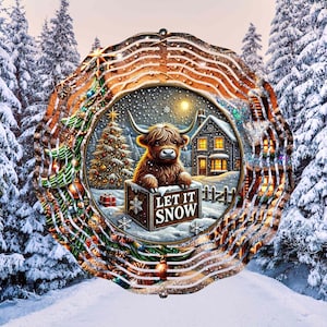 May include: A metal wind spinner with a winter scene featuring a Highland cow in a snowy landscape with a Christmas tree and a house. The spinner has a circular design with a brown wooden background and a white border. The text "Let It Snow" is on a sign in front of the cow.