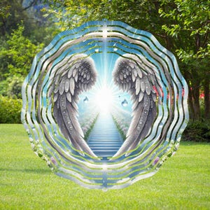 May include: A circular artwork featuring angel wings framing a bright light and a staircase leading upwards. The wings are detailed with gray and white feathers, set against a backdrop of a blue sky and green landscape.