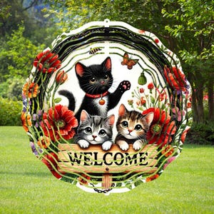 May include: A metal wind spinner with a circular design featuring three cartoon cats and a welcome sign. The cats are surrounded by flowers and leaves. The wind spinner is black, white, and red.