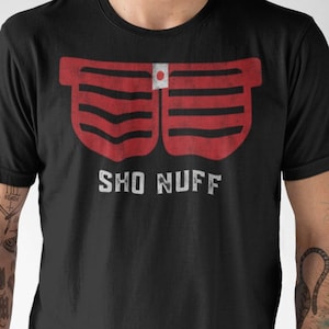 May include: A black t-shirt with a red graphic of a pair of sunglasses with a Japanese flag on the lens. The text "SHO NUFF" is printed below the sunglasses.