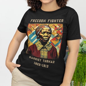 Könnte beinhalten: Schwarzes T-Shirt mit einer Vintage-Illustration von Harriet Tubman. Die Illustration ist von geometrischen Formen in Rot, Gelb, Blau und Grün umgeben. Der Text "FREEDOM FIGHTER" befindet sich über der Illustration und "HARRIET TUBMAN 1822-1913" darunter.