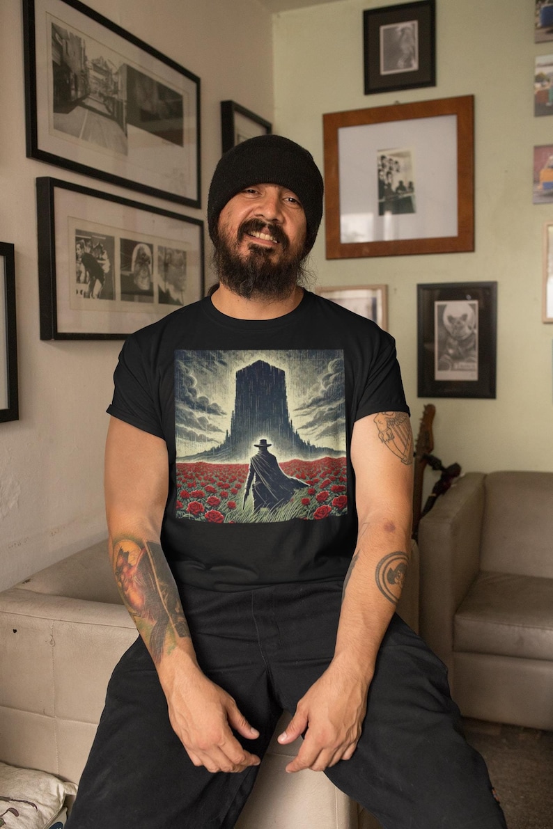 The shirt portrays a lone gunslinger standing resolutely before an ominous, dark tower, surrounded by a vast field of crimson roses.A nod to Roland Deschain of Stephen King's Dark Tower series.