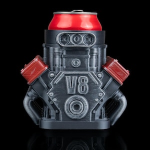 May include: A black and gray V8 engine-shaped can cooler with red accents. A red soda can sits in the cooler. The cooler has the text "V8" on the front.
