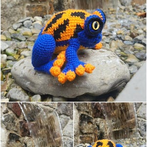 May include: A crocheted frog toy featuring a vibrant orange and black patterned back with a solid blue body, limbs, and head. The frog has large, prominent yellow eyes with black pupils and orange-tipped toes, crafted with detailed yarn stitching.