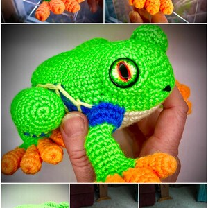 May include: A handcrafted crochet frog toy featuring a bright green body, orange feet, and blue accents along the sides. The plush figure has large, detailed eyes with red and black irises and a cream-colored underside, showcasing intricate yarn stitching throughout.